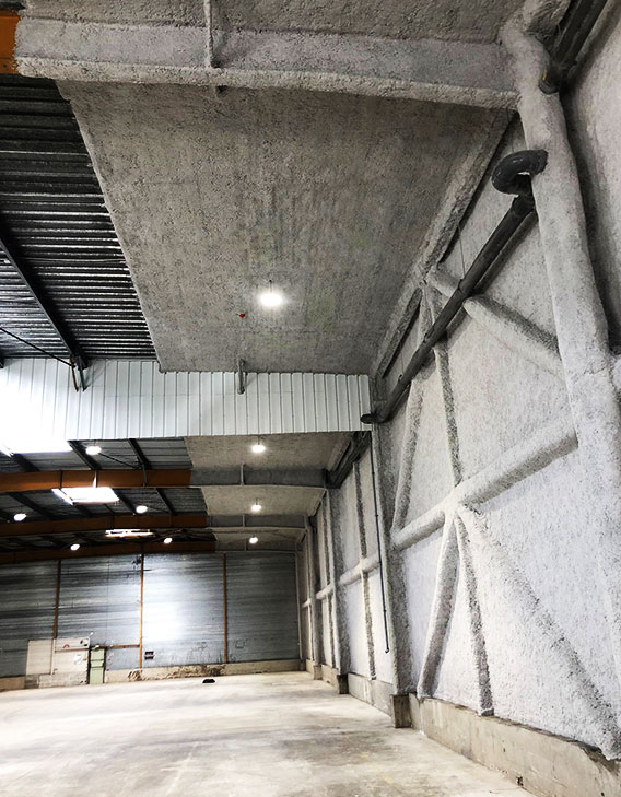 Travaux d'isolation acoustique par flocage fibreux dans un bâtiment industriel pour réduire les nuisances sonores.