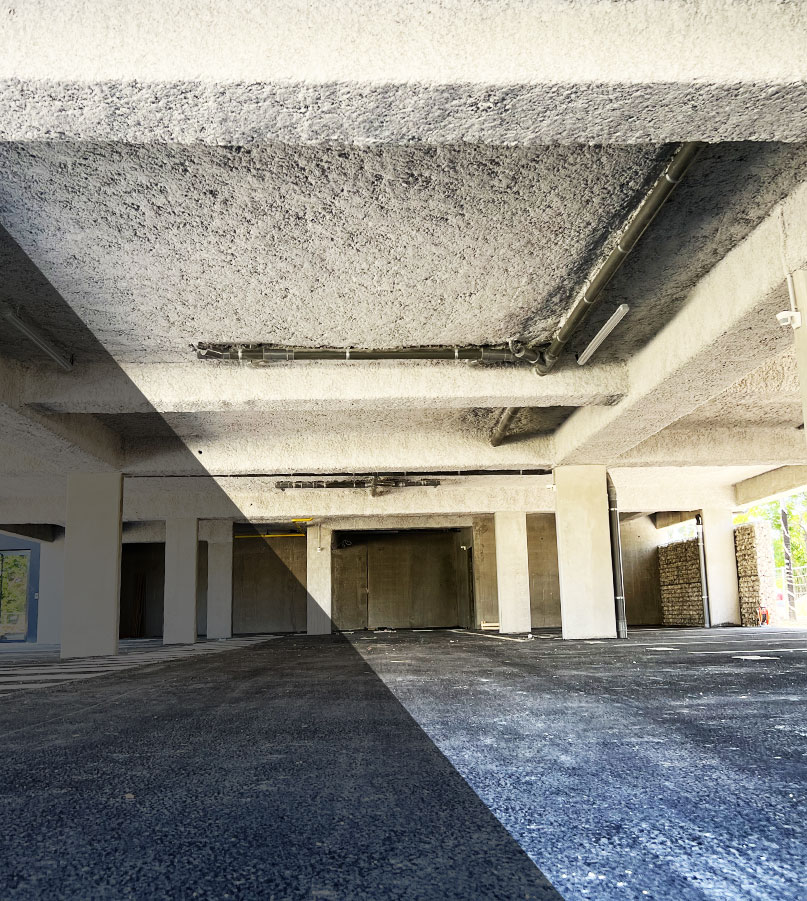 Travaux d’isolation thermique d’un parking par projection de laine minérale sur plafond, pour renforcer la performance énergétique du bâtiment.