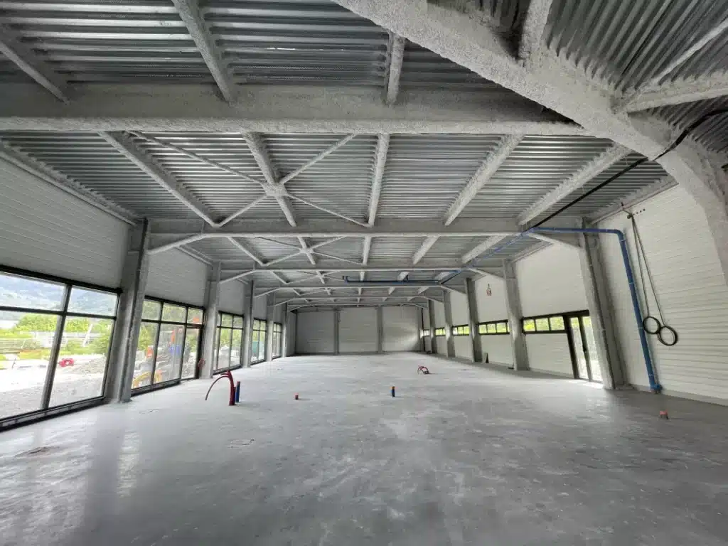 Flocage fibreux de laine minérale projetée sur charpente métallique, technique de protection incendie passive pour bâtiment recevant du public.